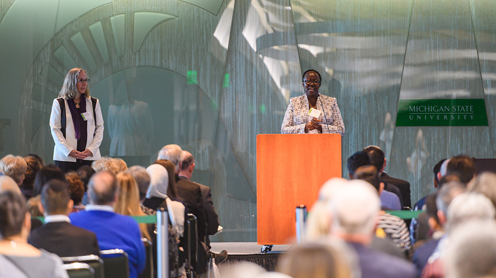 A woman standing at a podium accepting her award in front of an audience